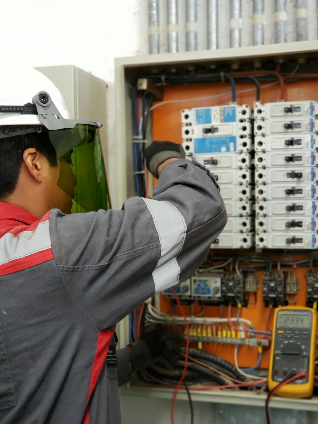 Técnico inspecciona panel eléctrico abierto con interruptores y cableado.