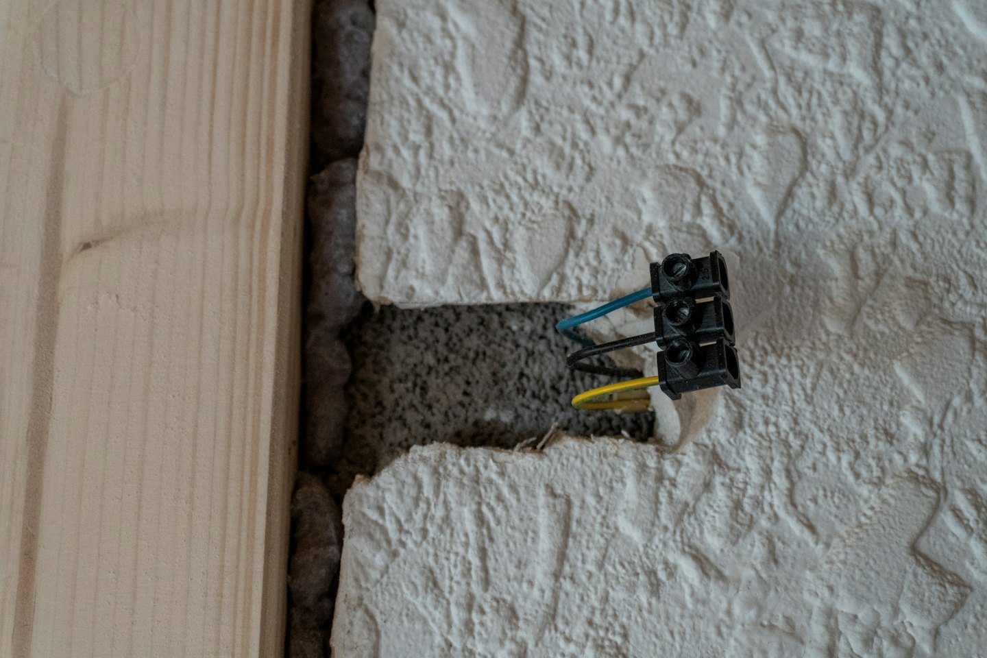 Electricista instalando cables azules y amarillos en una pared.