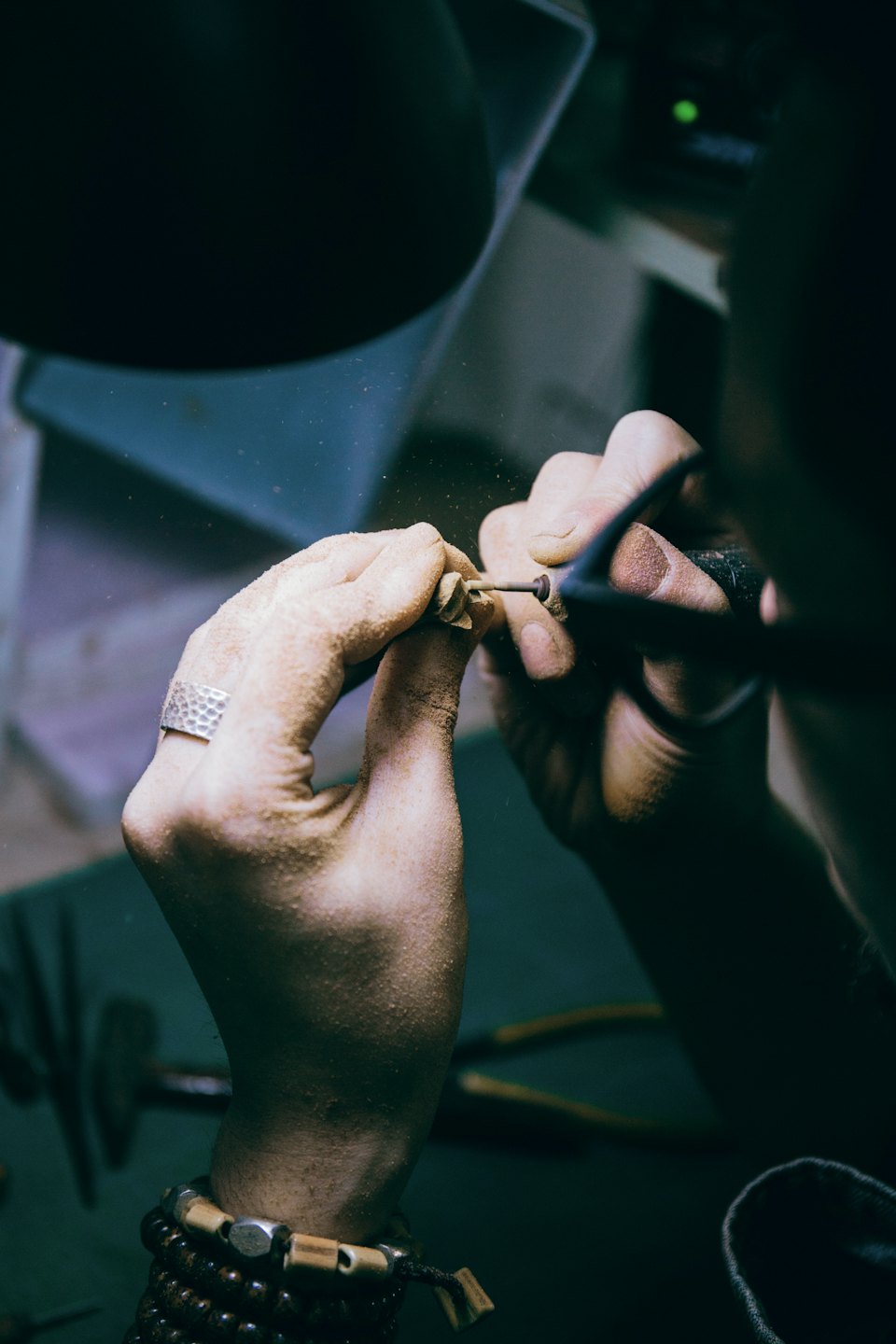 Manos dando forma a metal con una herramienta rotatoria.